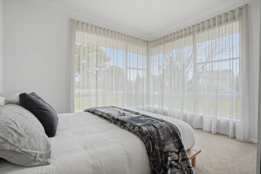A queen bedroom with corner windows over the lawn